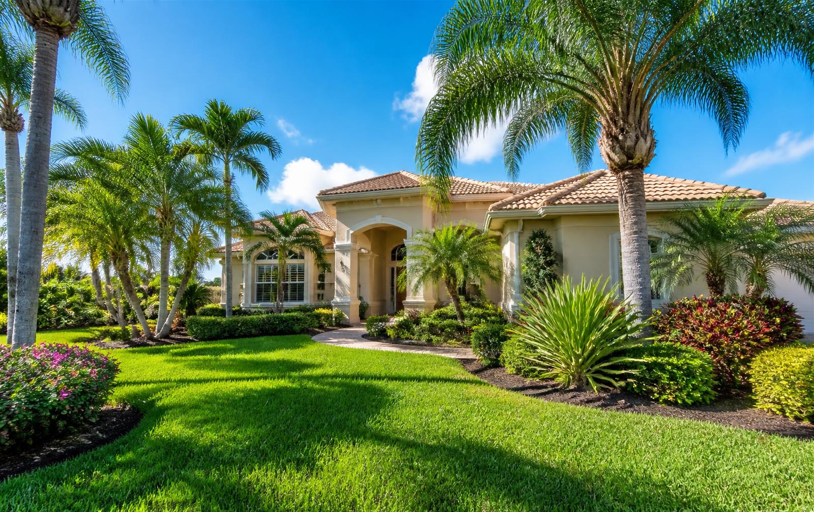 Florida front yard with palm trees, bright blue sky and neatly trimmed landscaping in Lee County
